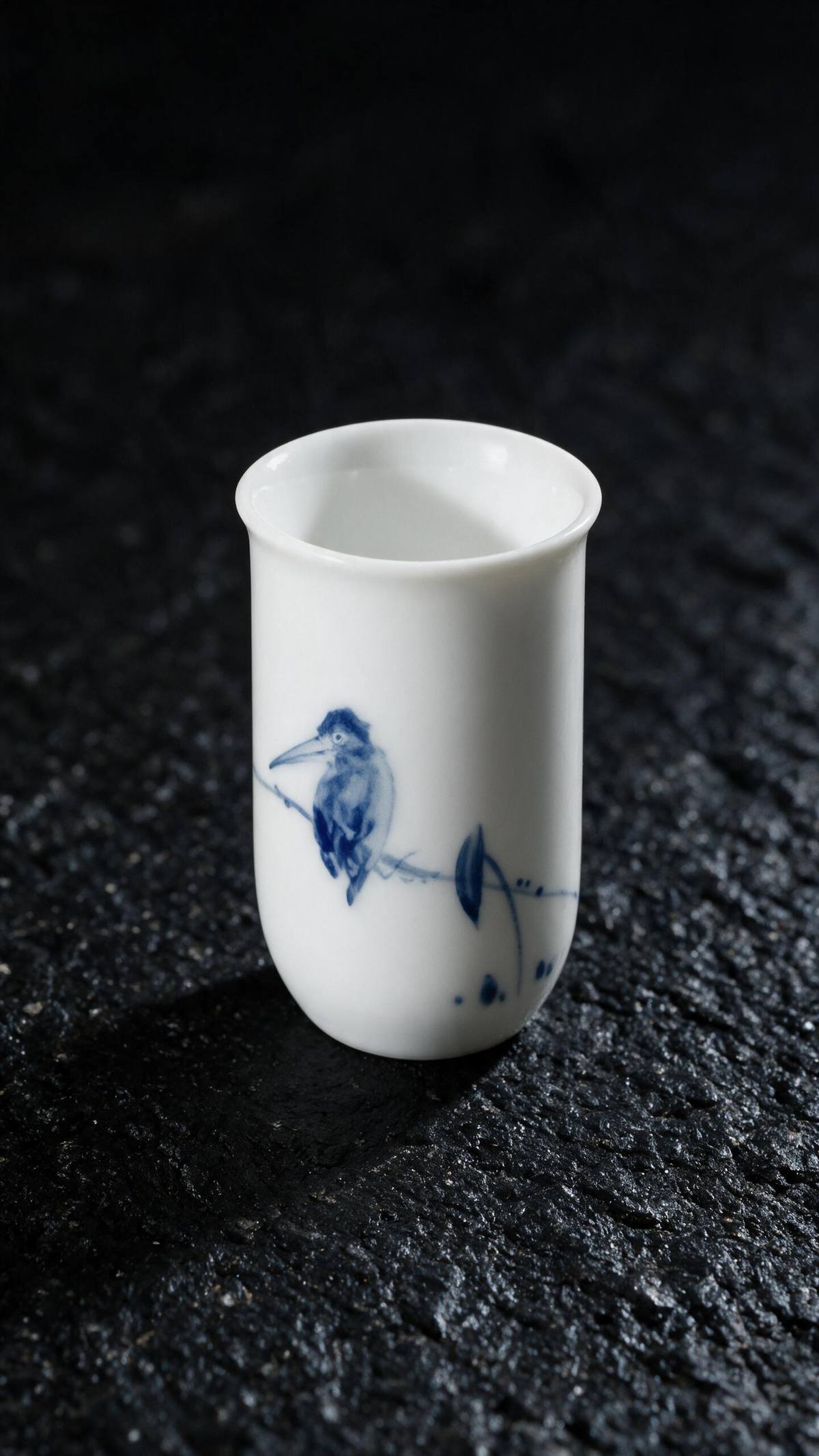Tall white tea cup with a cobalt-blue bird perched on a leafy branch