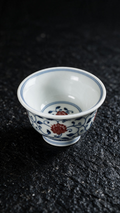 White tea cup with cobalt-blue floral scrolls, red blossoms and a matching flower inside